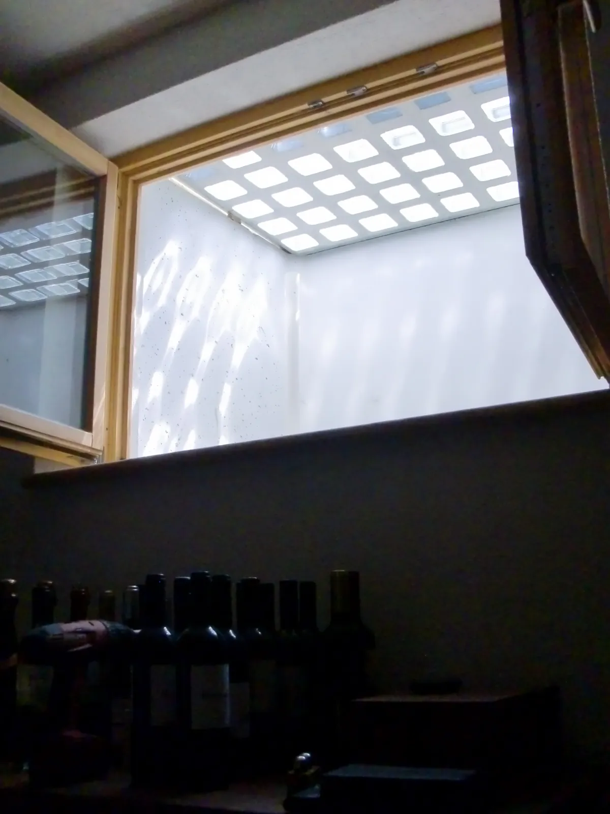 Blick aus dem Keller durch ein Fenster zu einer wasserdichten Lichtschachtabdeckung