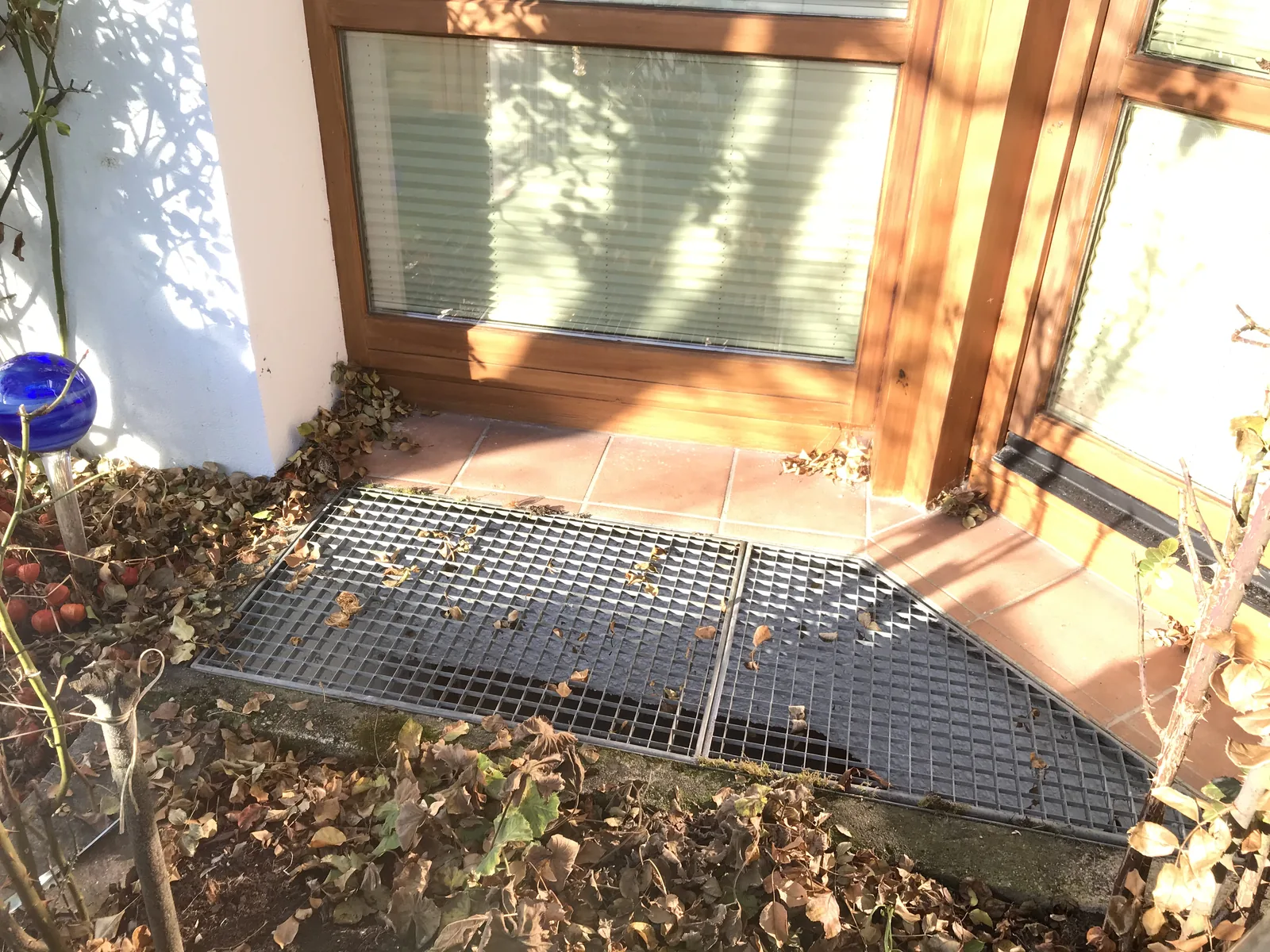 Vorher: Lichtschacht mit altem Gitterrost in Schräglage vor der Terrassentür – nur regensicher, kein Hochwasserschutz